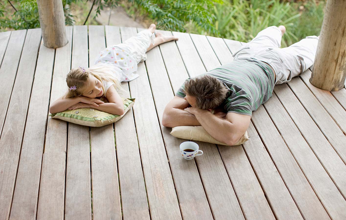 Zwei Personen liegen auf einer Holzterrasse im eigenen Garten